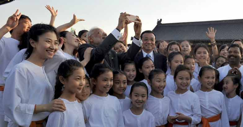 Indian Prime Minister Narendra Modi (C) takes a selfie along with Chinese Premier Li Keqiang (centre, R) and children during the Taiji and Yoga event at the Temple of Heaven park